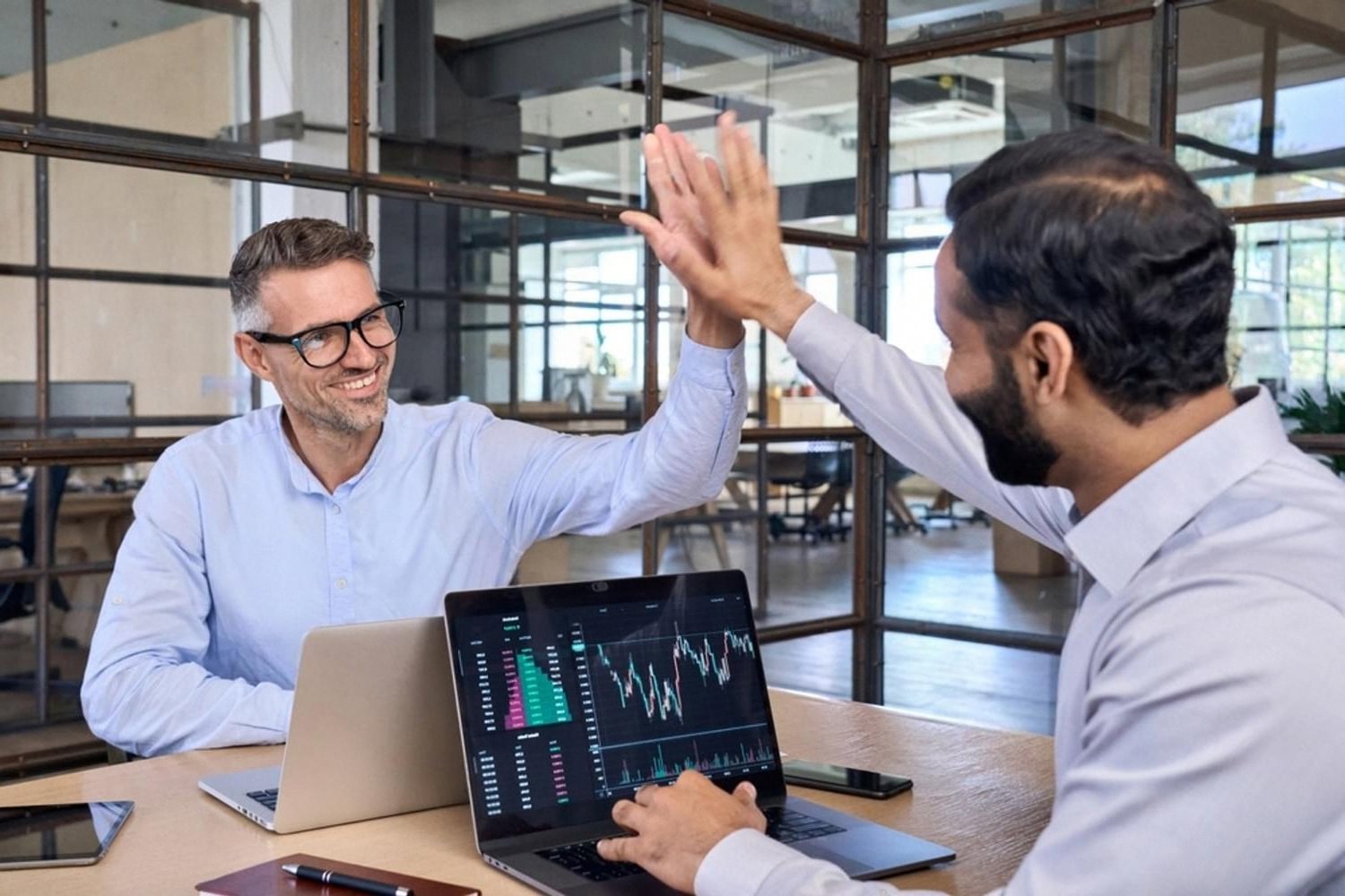 Two business leaders celebrating IT strategy success in a modern UAE office